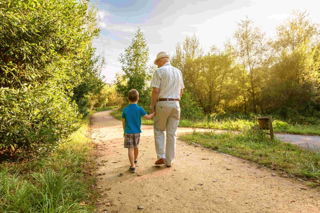 Grandfather walking in park with grandchild.